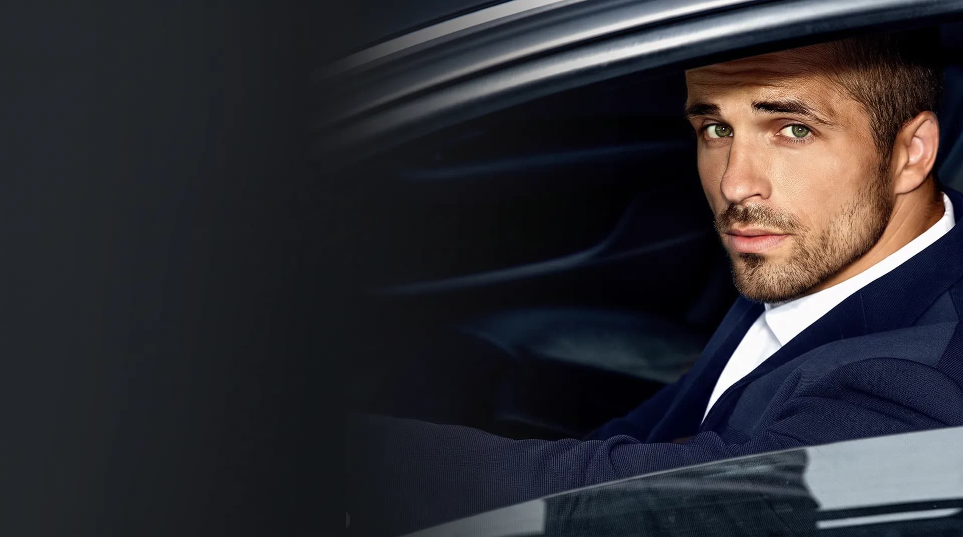 Man in a tailored navy suit seated in a luxury car