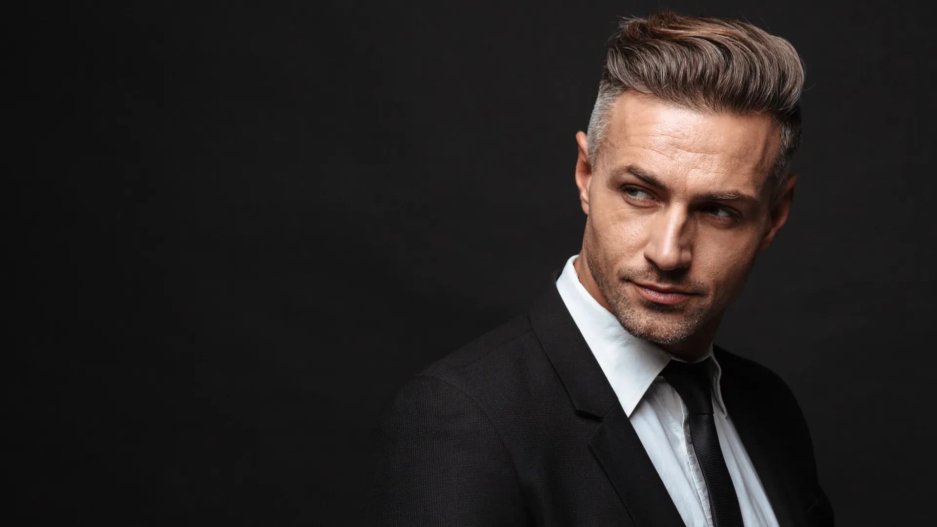 Mature man in a black suit against a dark background